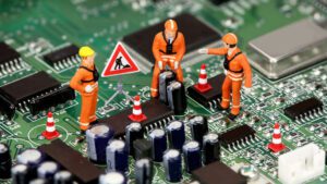 Little construction figurines positioned on circuit board as if working
