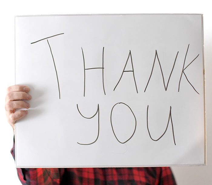 Person holding Thank You sign in front of their face