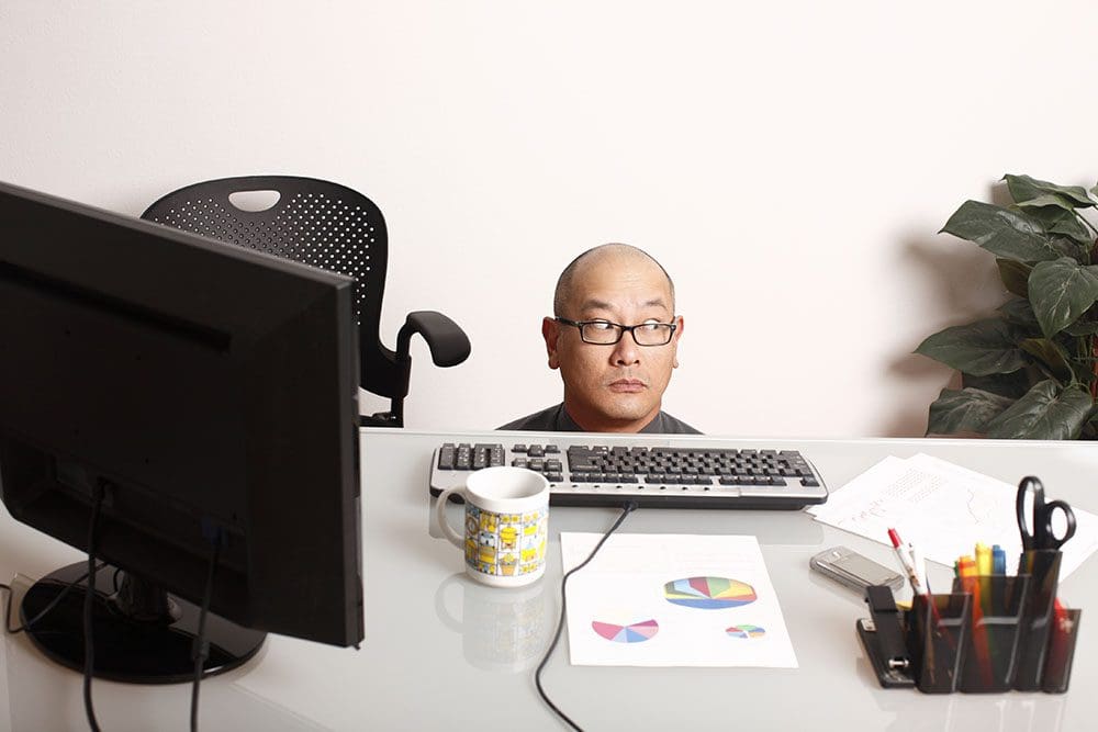 Man sinking down to hide behind his desk