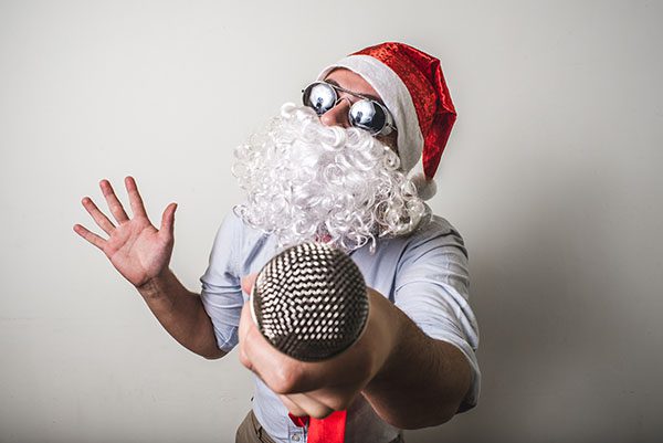Man wearing Santa hat and beard while singing
