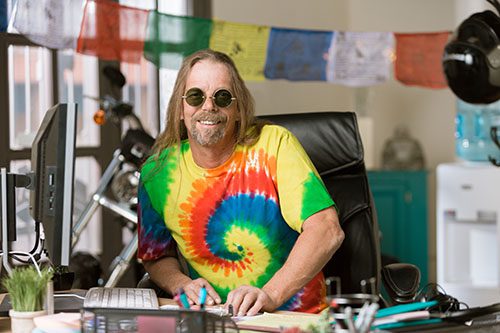Man in tie-dyed shirt at desk in colorful office