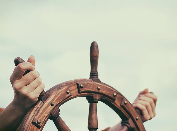 Hands on wheel navigating a ship