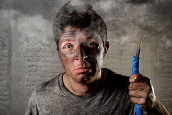 Man with soot covered face holding a spliced cable