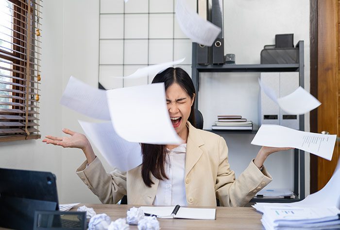 Upset woman in office after throwing papers in air