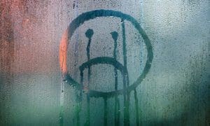 Sad face that appears to be crying drawn on a steamed up window