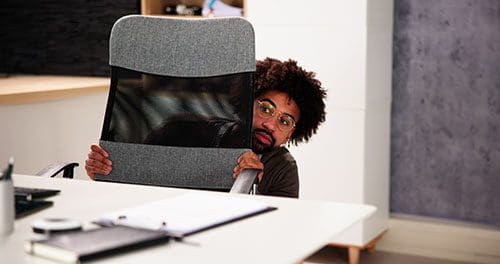 Man hiding behind office desk