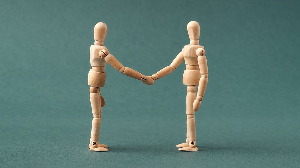 Two wooden figures shaking hands