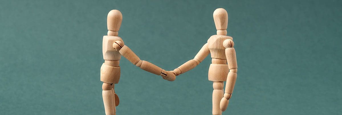 Two wooden figures shaking hands