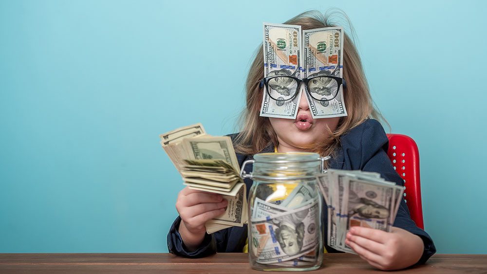Child with money jar, money in her hands and also money held in place over her face with her eyeglasses