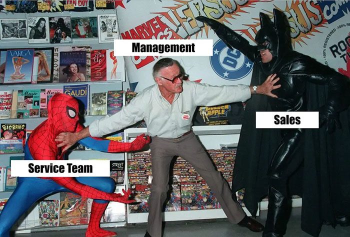 Meme of Stan Lee keeping Spiderman and Batman from attacking each other. Spiderman is labeled Service Team, Batman is Sales and Stan Lee is Management