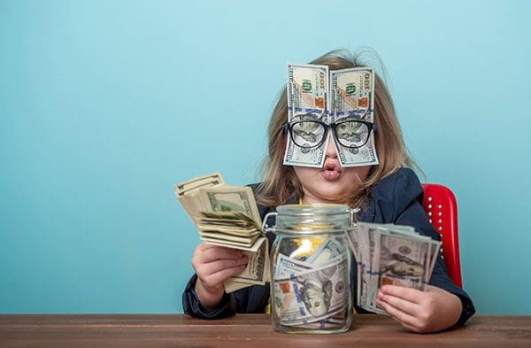 Child with money jar, money in her hands and also money held in place over her face with her eyeglasses