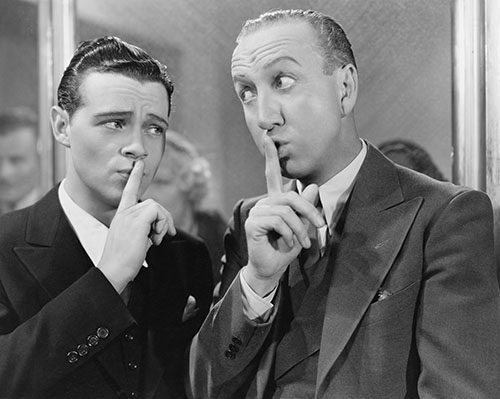 Two men with fingers to their lips in the classic quiet pose