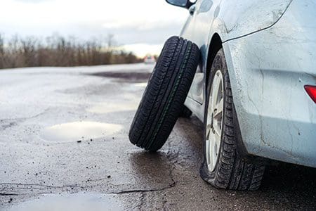 Car with flat tire and spare leaning on car