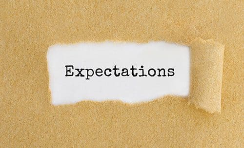 Ripped brown paper reveals the word Expectations